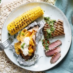Corn in cob, jacket potato and steak dish