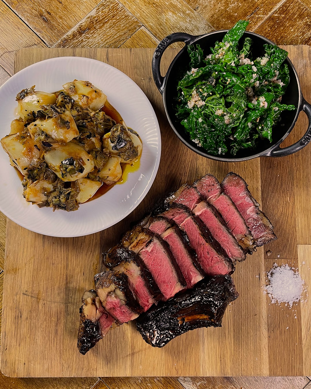 Carved beef on chopping board with potatoes and vegetables