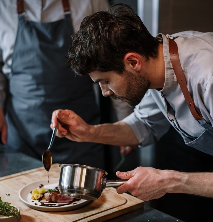 chef pouring sauce on steak