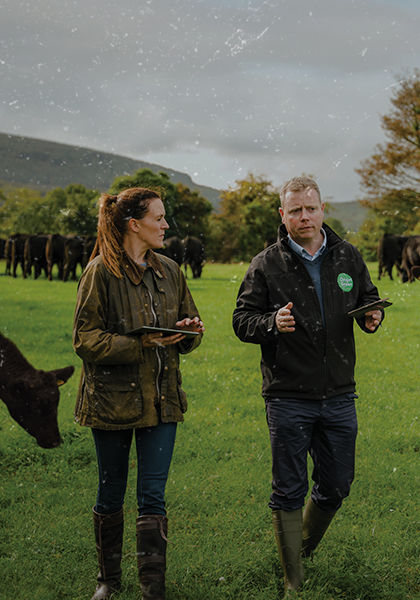 An farm auditor taking to a farmer while walking through a field