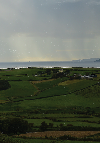 Green fields with rain falling on the headland in the distance