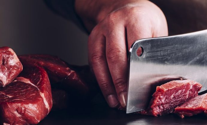 Cutting raw beef with a butchers knife